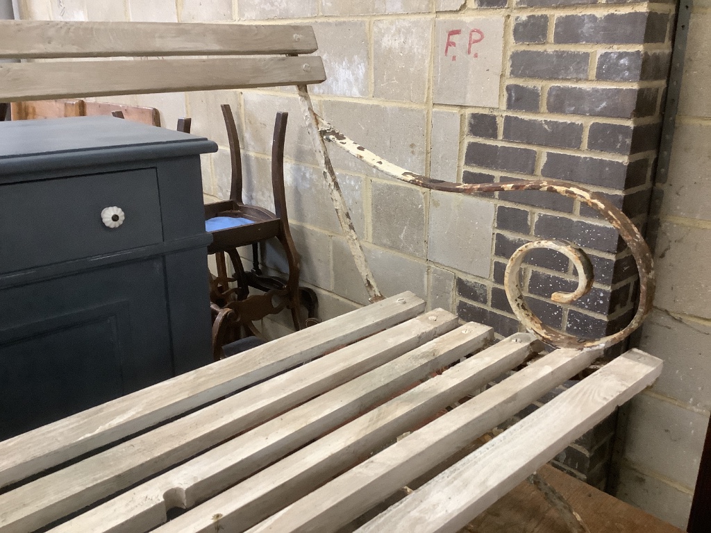 A white painted wrought iron garden seat with wooden slatted seat, width 121cm